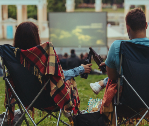 A couple relaxing in front of a movie on the lawn at Porte Apartments
